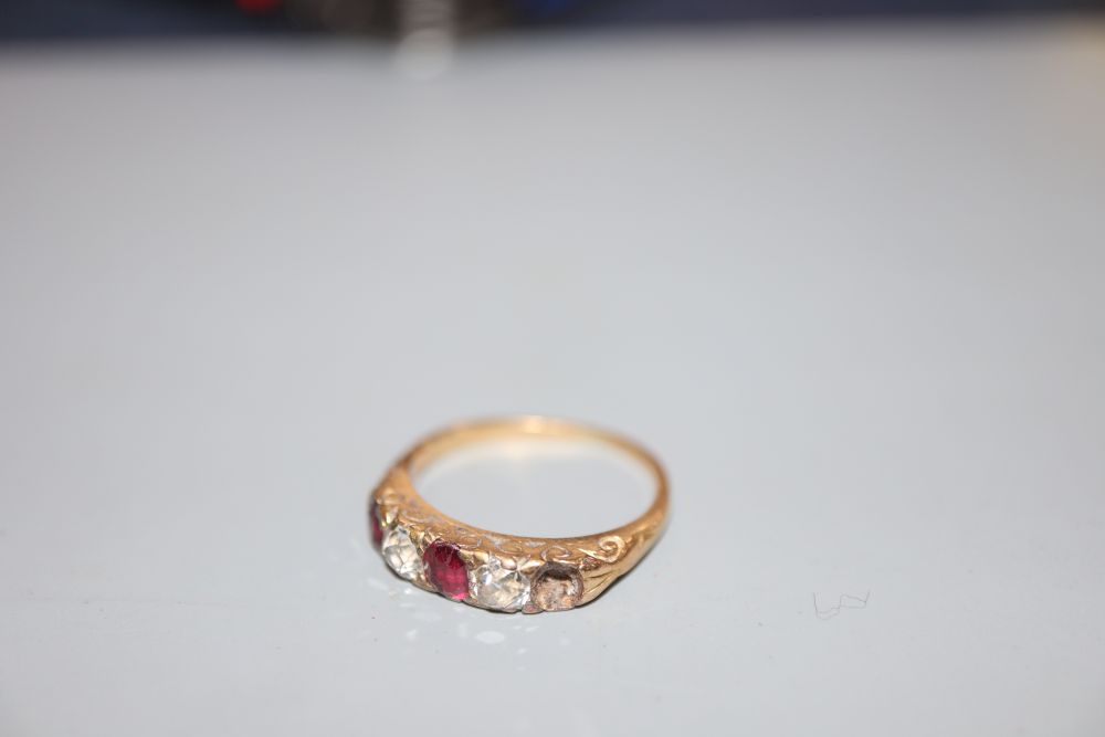 An early 20th century yellow metal, two(ex three) stone ruby and two stone diamond half hoop ring, size H, gross 3.1 grams.